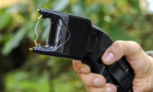 A hand holding a black, slightly curved stun gun 